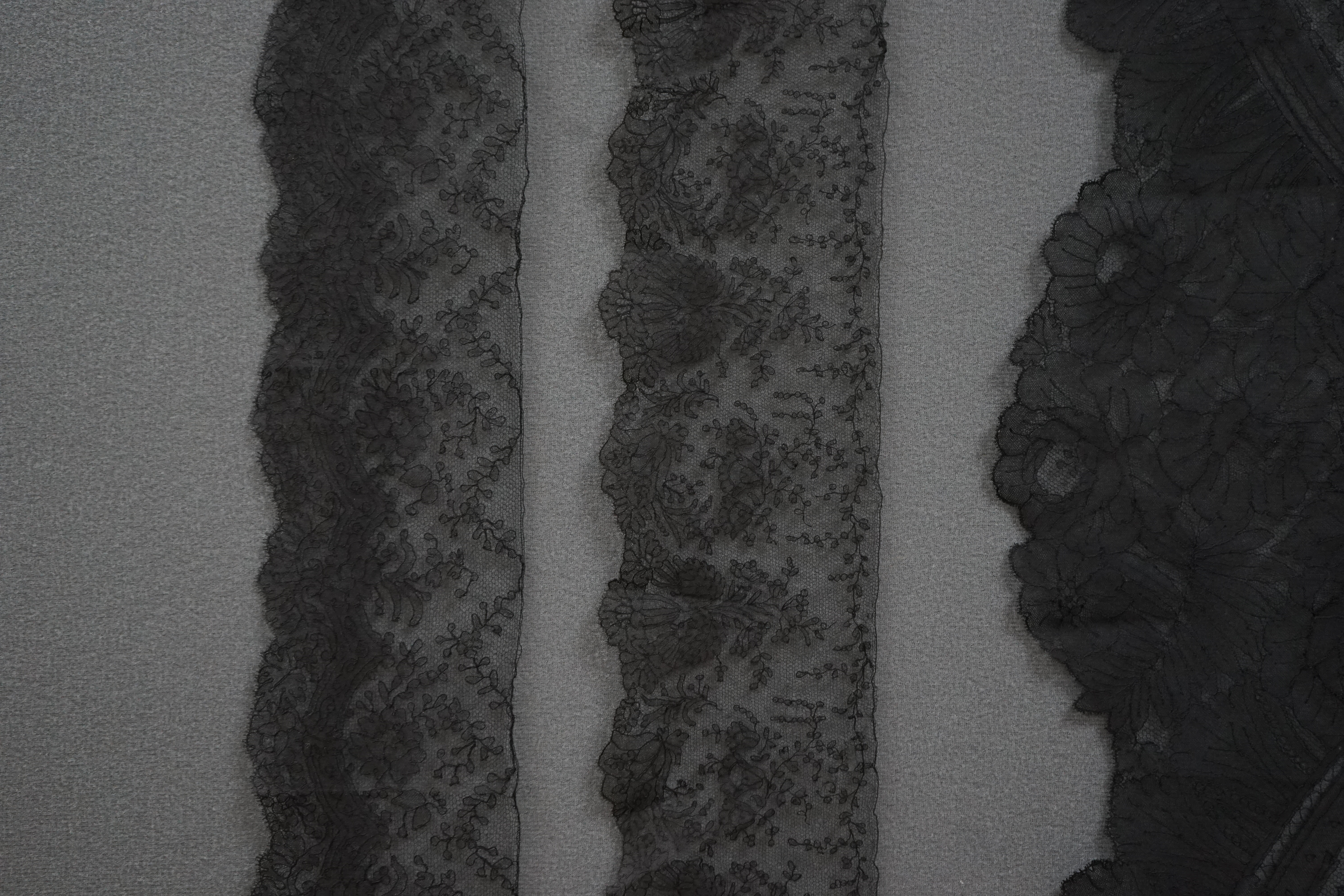 A black silk flounce of wide Chantilly lace trimming and two similar narrower Chantilly trimmings, the flounce with a deep floral design and scalloped edge, 496cm long x 46cm deep, the narrow trimmings, both with matchin